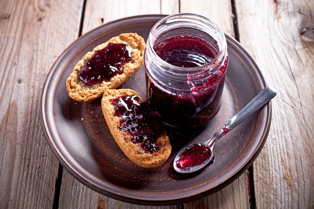 Black currant jam in glass jar and crackers