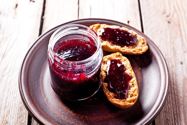 Black currant jam in glass jar and crackers 