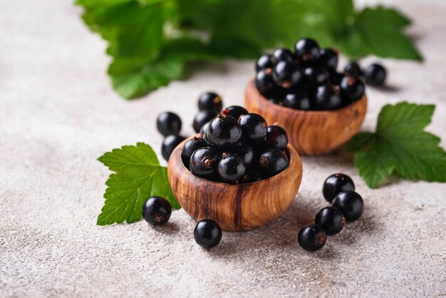 Black currant with leaves in wooden bowls