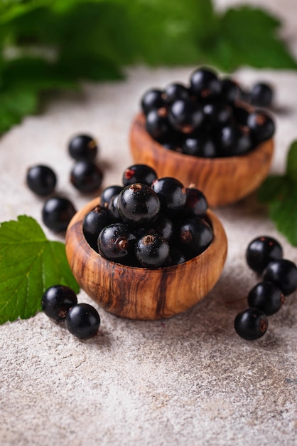 Black currant with leaves in wooden bowls