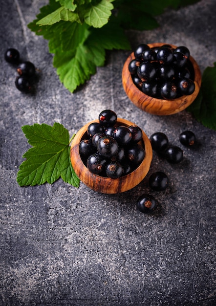 Black currant with leaves in wooden bowls