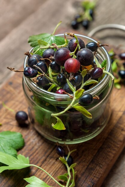 Black currant on wooden table with leaf sprig