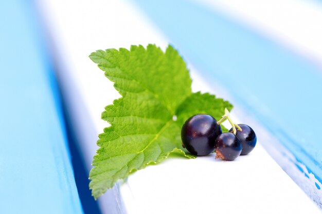 Black currants with leaf on a wooden plank