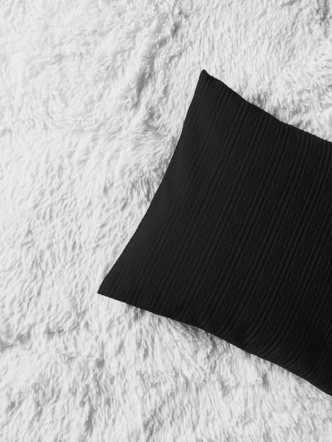 Black cushion throw pillow on white fluffy plaid blanket as flat lay background bedroom top view and...