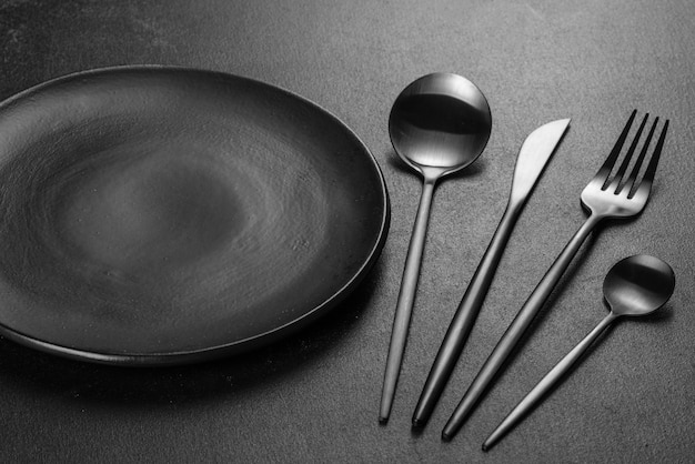 Black cutlery on a concrete dark table. Dining table preparation