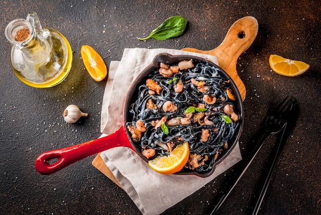 Black cuttlefish ink spaghetti pasta with seafood, olive oil and basil