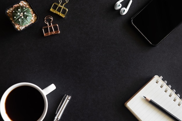 Black desk office with laptop, smartphone and other work supplies with cup of coffee. Top view with copy space for input the text. Designer workspace on desk table essential elements on flat lay.