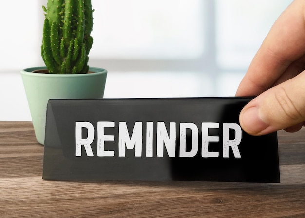 A black desk sign that says reminder on it