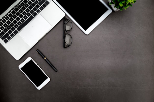 Black desk with blank notebook and other office supplies.