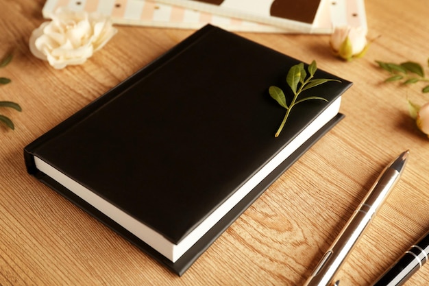 Black diary and accessories on wooden table