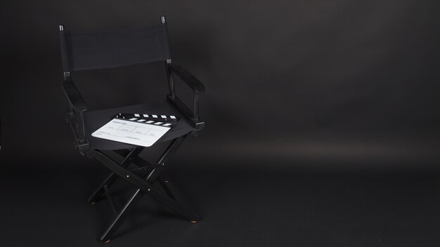 Black director chair and Clapperboard or clap board or movie slate on black background.