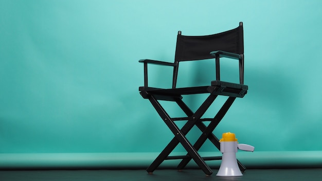 Photo black director chair with megaphone on green or tiffany blue or mint background.it use in videography or film cinema industry