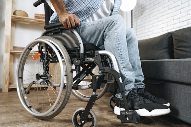 L'uomo disabile nero si siede sulla sedia a rotelle a casa