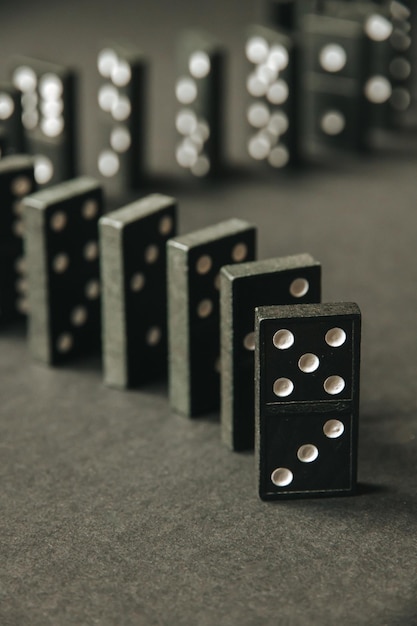 Black dominoes chain on a dark table background. Domino effect concept