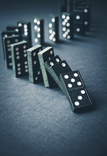 Black dominoes chain on dark table background