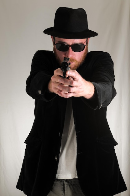 Photo black dressed young man holding a pistol gun