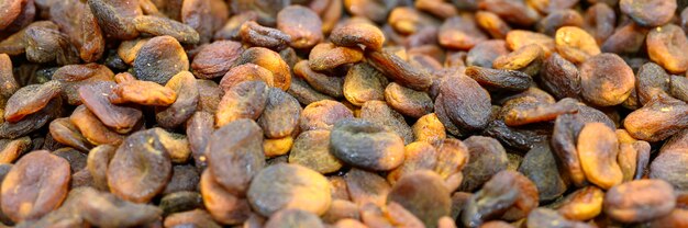 Black dried apricots a pile of dry fruits as a background.