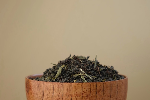 Black dry tea pouring in a bowl. pile of mix black and green
tea leaves. close up macro. front view