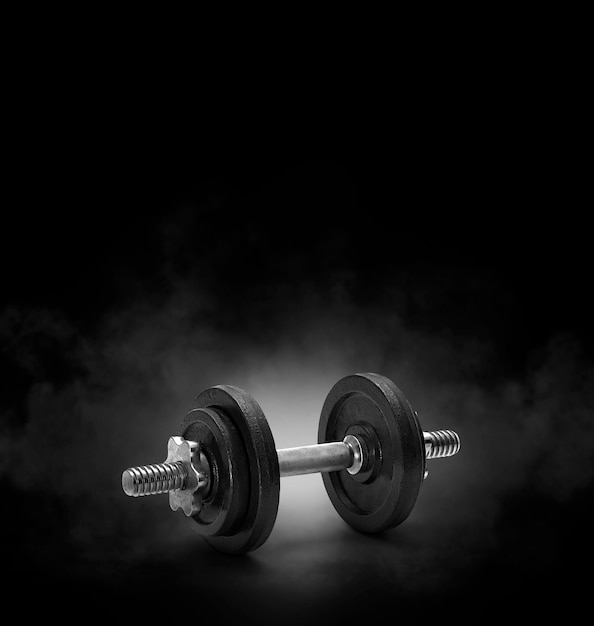 Photo black dumbbell with on black background with smoke