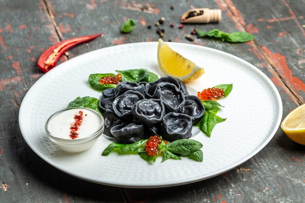 Black dumplings stuffed with fish and caviar. ravioli