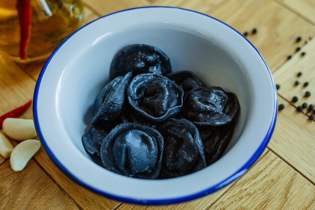 black dumplings in a white plate on the table.