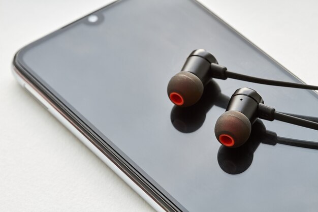 Black earphones lie on the modern smartphone