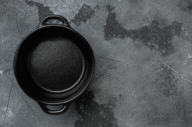 Черный пустой глиняный горшок с копировальным пространством для текста или еды с копировальным пространством для текста или еды, плоский вид сверху, на фоне серого каменного стола