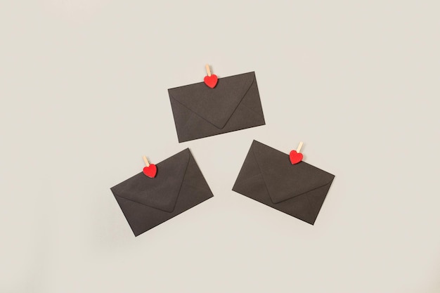 Черные конверты с красными сердечками на сером фоне