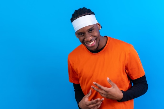 Black ethnic man in orange clothes on a blue background having fun smiling and party dancing