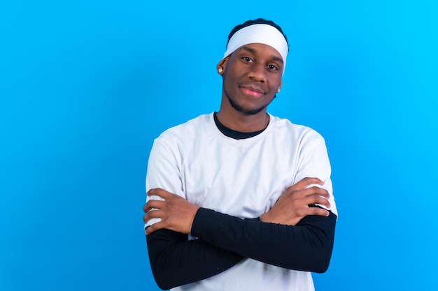 Black ethnic man in white clothes on a blue background arms crossed