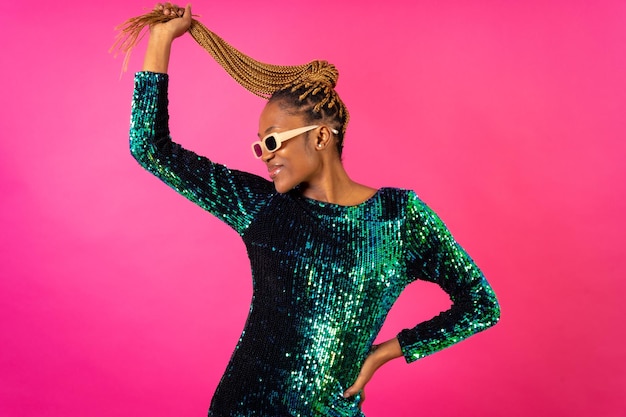 A black ethnic woman with braids dancing at party on a pink background