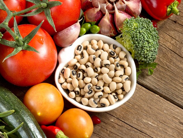 Black eyed peas and vegetables border on a wooden table close up