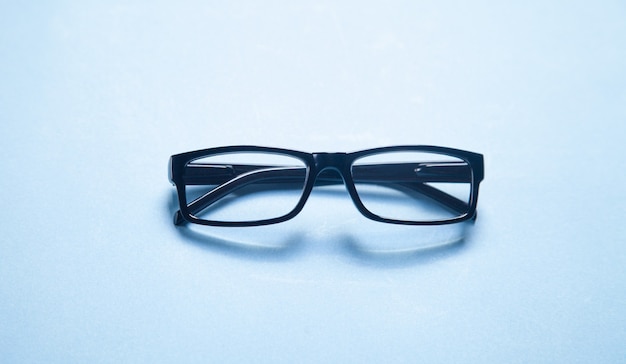 Black eyeglasses on the blue background.