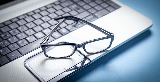 Black eyeglasses on the laptop keyboard