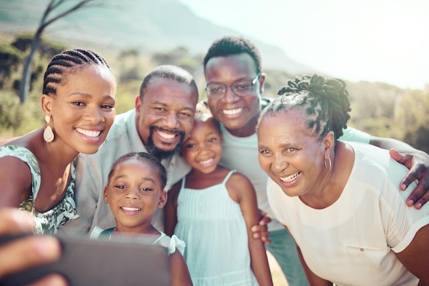 Black family taking a selfie with happy children in nature together in fun natural outdoors in summer freedom smile and senior woman with african kids smiling for phone camera on a holiday vacation