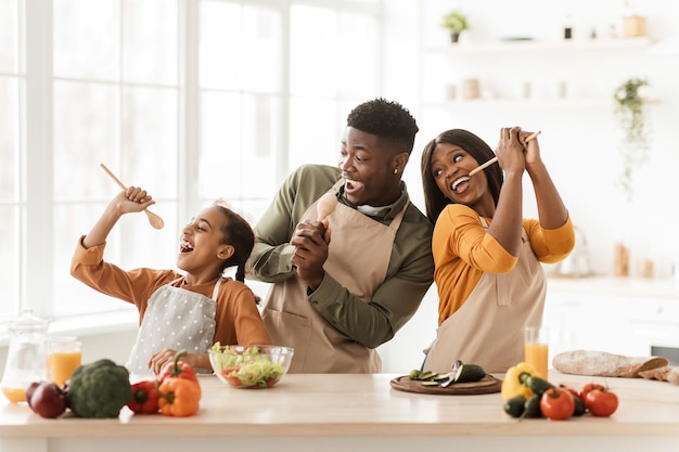 Black family of three cooking having fun singing in kitchen