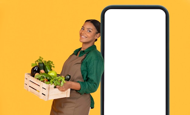 Black farmer woman leaning on phone empty screen yellow background