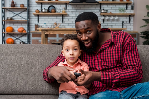 写真 黒い父と息子がテレビを見ています