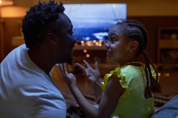 Black father and daughter watching tv