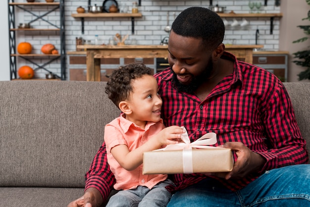 Photo black father giving gift box to son