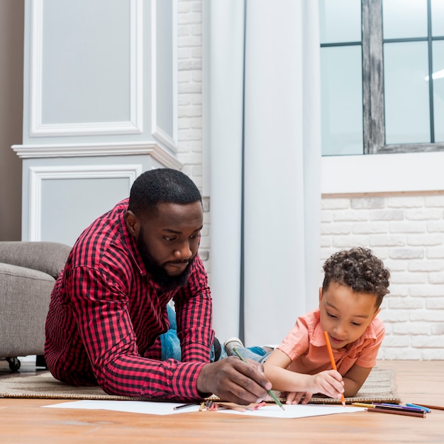 Photo black father and son drawing on floor