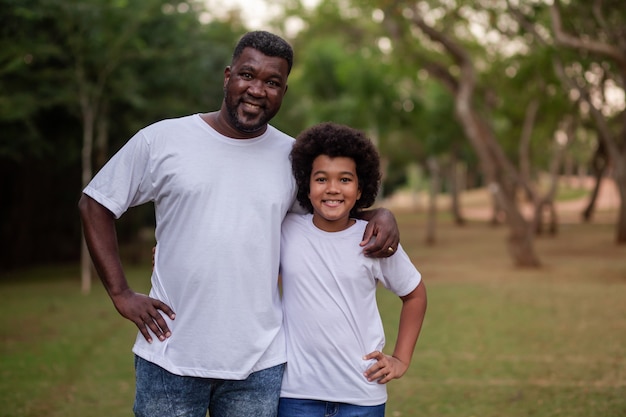 Nero padre e figlio nel parco tenendosi sorridenti guardando la telecamera