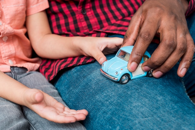 black father and son playing with small toy car