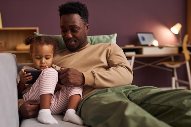 Photo black father with cute little girl using digital tablet at home