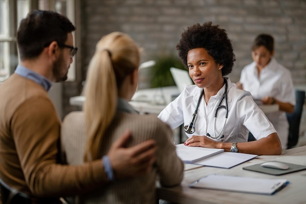 Black female doctor having consultations with a couple about their medical insurance at clinic