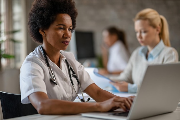 Black female doctor using computer while typing medical reports in her office