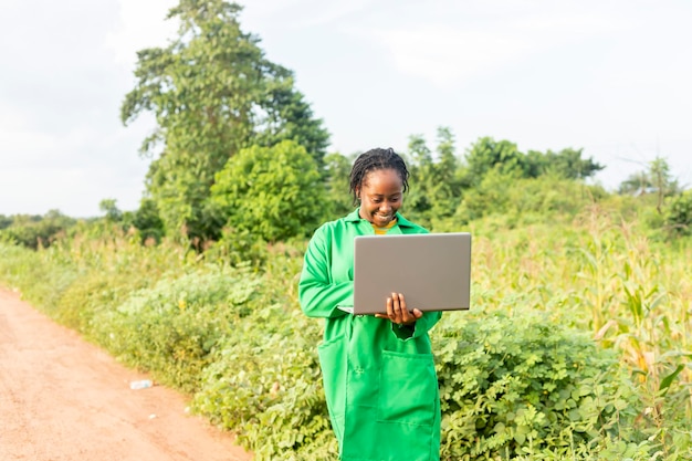 Black Female farm agronomist checking an agricultural field using laptop