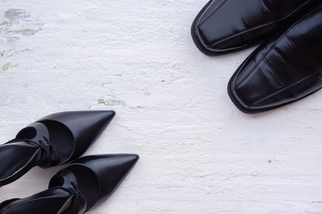 Black female and male shoes on white wood Floor. 