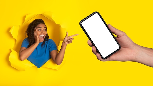 Black female pointing at cellphone posing in torn paper background