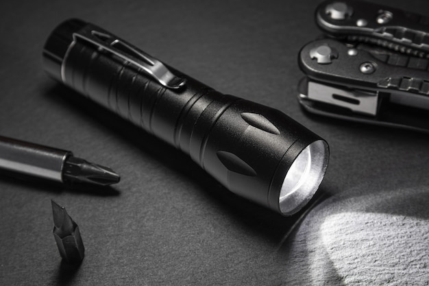 Black flashlight on the stone surface. Tools for work, search and tourism ..